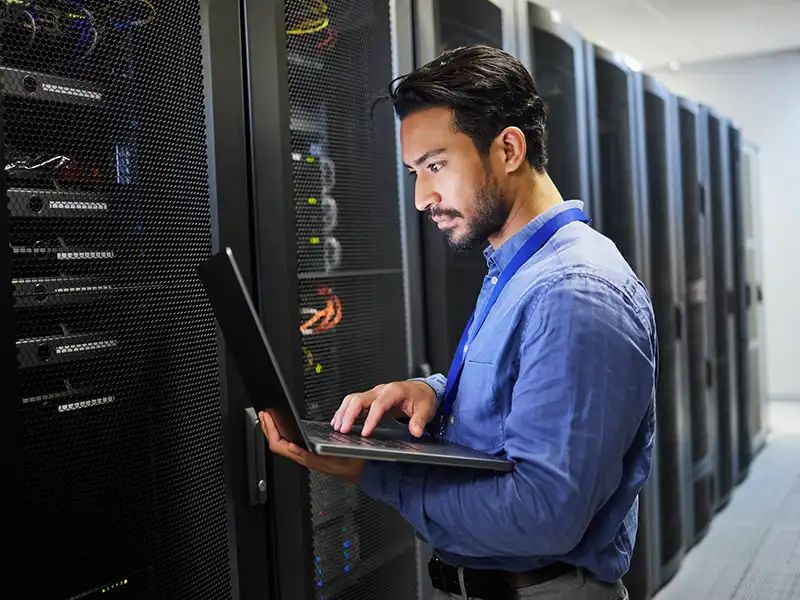 Man using his laptop while in a server room